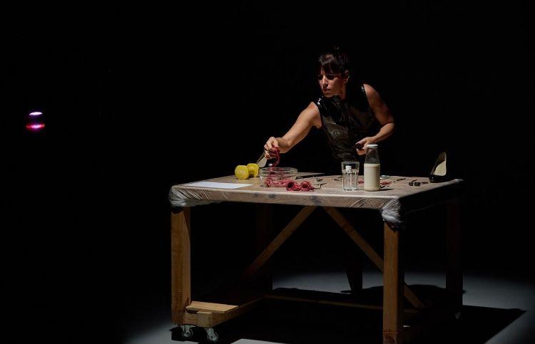 Una mujer en una mesa realiza actividades cotidianas. Puesta en escena del proyecto de arte Quiero ser un animal hembra