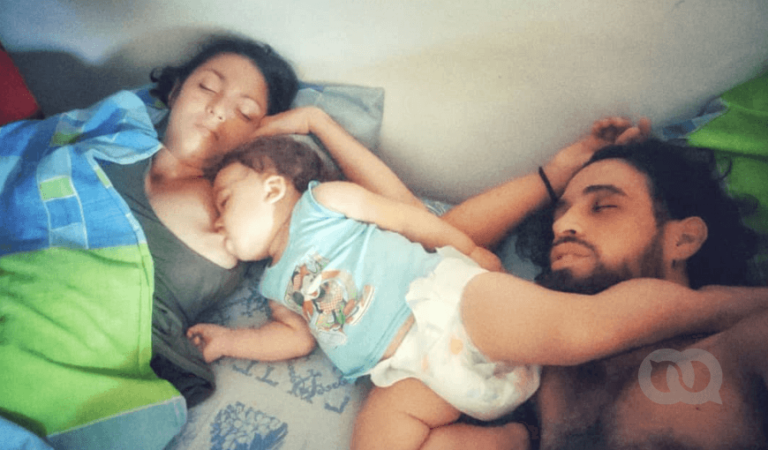 Madre y padre haciendo colecho con su bebé. La madre amamanta a su hijo