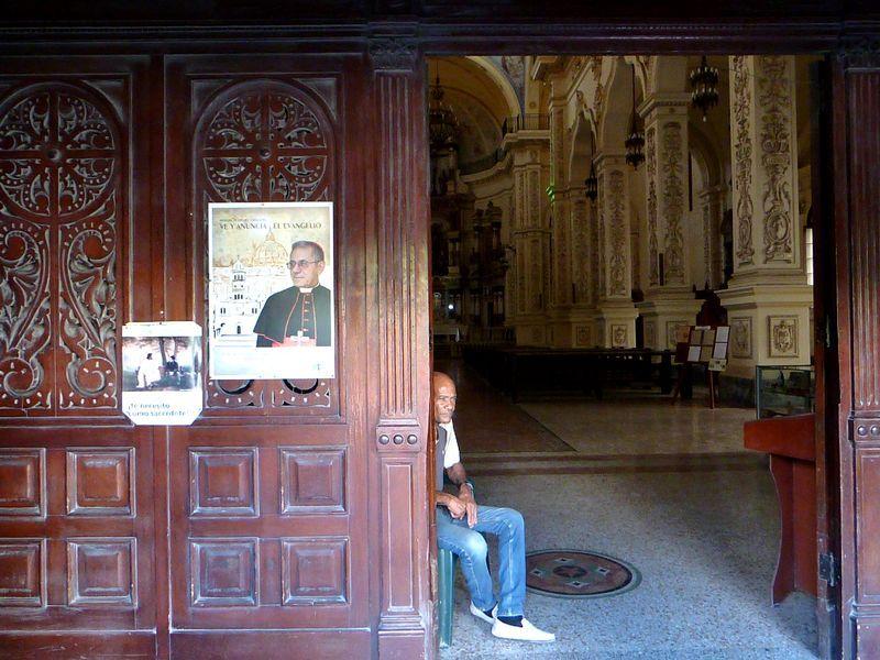 Un hombre mira hacia la calle desde la puerta de entra en una iglesia en La Habana