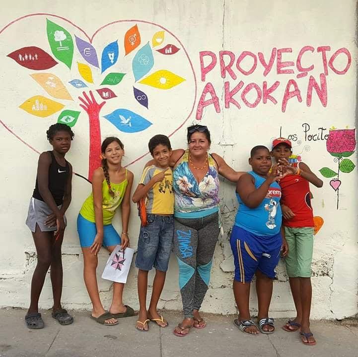 Niñas y niños posando delante de un mural pintado en una pared en el  proyecto Akokán, Los Pocitos. Construyendo ciudad