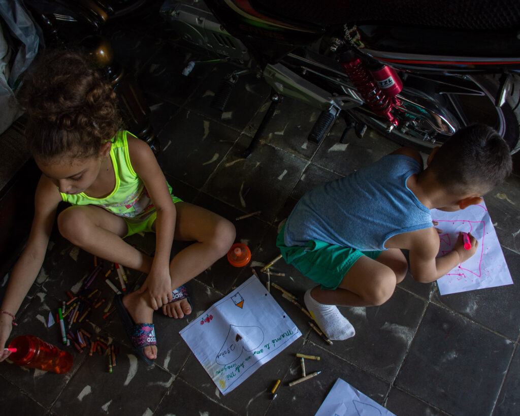 Una niña y un niño dibujan sentados en el piso. Salud mental para niños