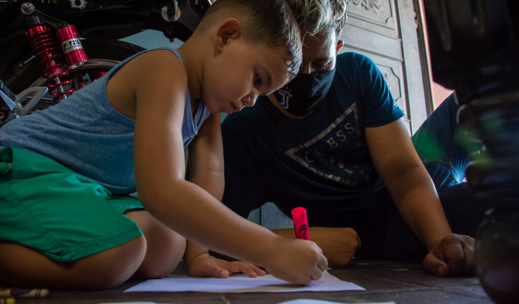 Un niño y un hombre dibujan sentados en el piso. Salud mental para niños