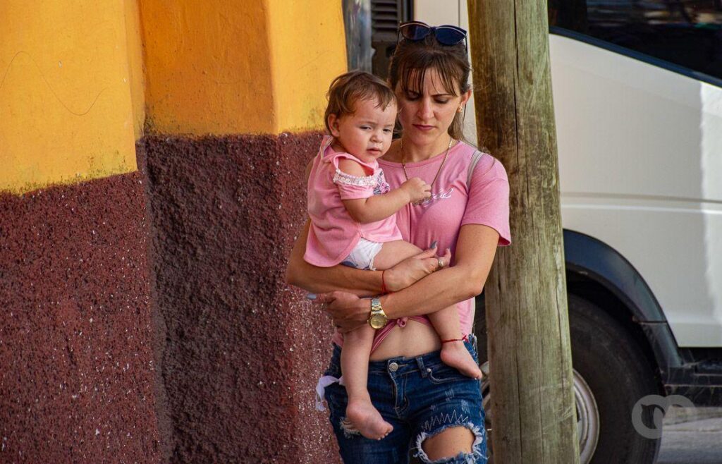 Mujer carga a su bebé por la calle. 