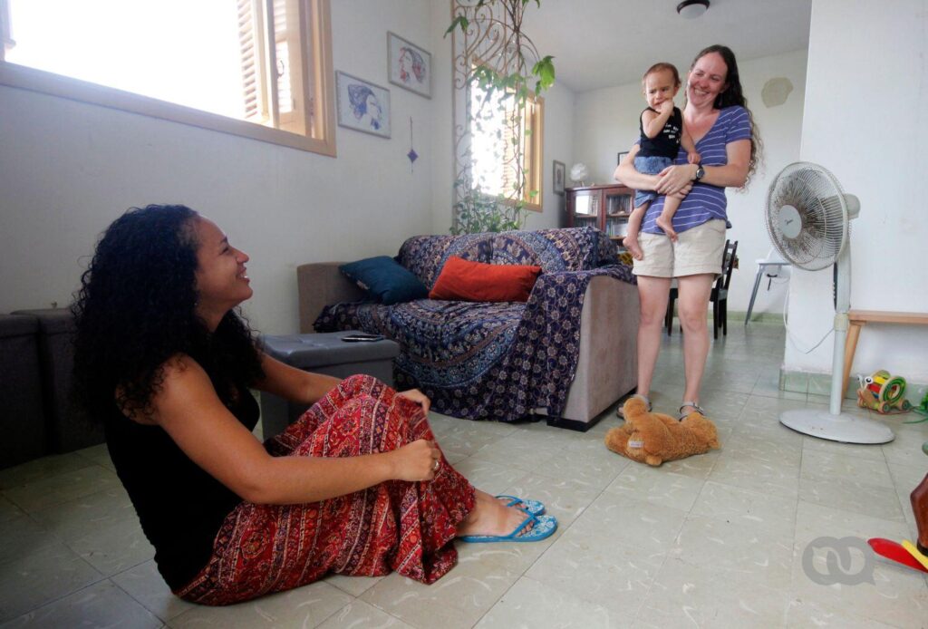 La familia que han creado Dachelys y Hope en la sala de su casa, una de las madres carga al hijo en común. Es el primer bebé con dos madres en Cuba. (Madre)