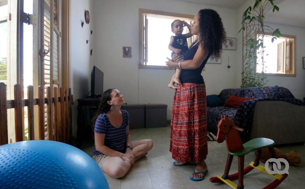 La familia formada por Dachelys y Hope en la sala de su casa, en su vida cotidiana. Es el primer bebé con dos madres reconocido en Cuba. (Madre)