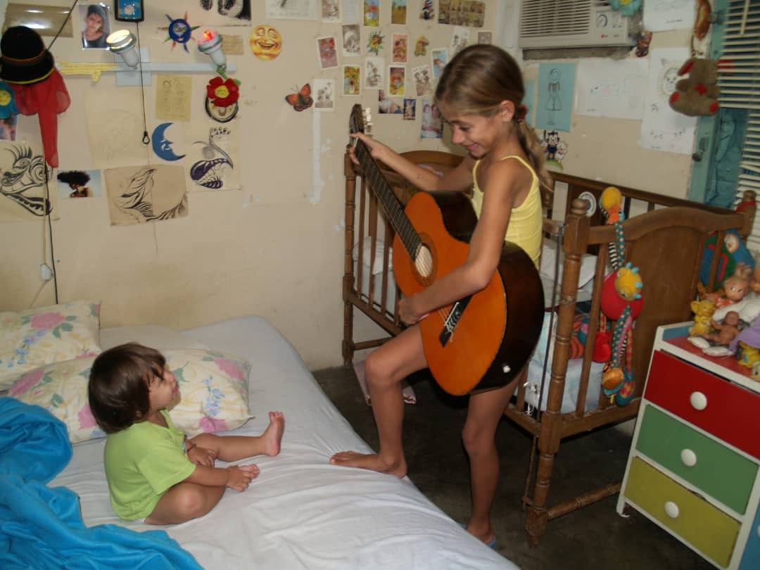 niña toca guitarra a una bebé